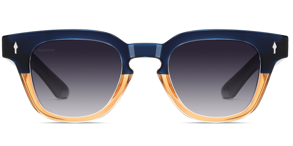 A pair of square sunglasses with a translucent navy blue top frame, a warm amber-tinted bottom frame, and dark gray gradient lenses. The temples are black with small white logo accents.