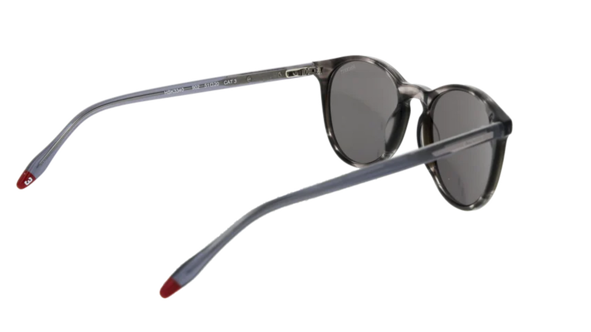 Round sunglasses with a smoky gray acetate frame, dark gray lenses, and red-accented temple tips, shown on a plain white background.