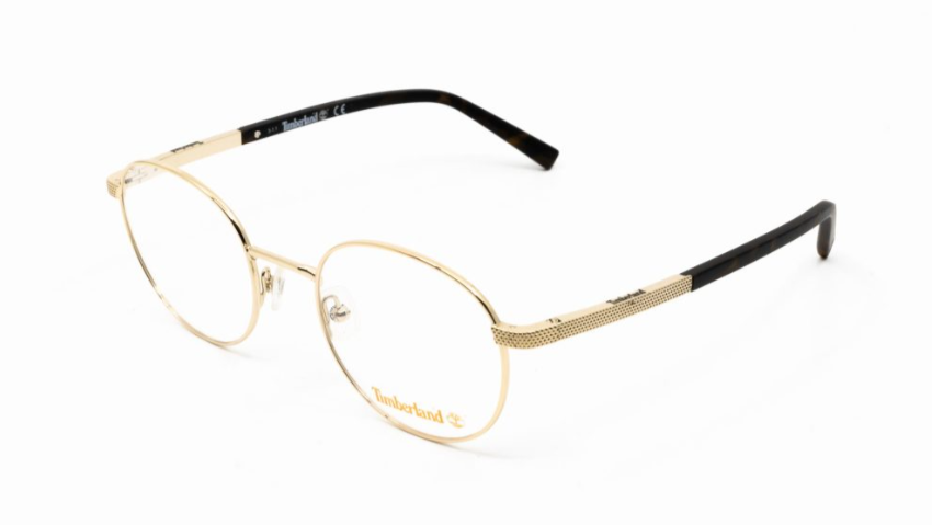 Timberland eyeglasses featuring gold-tone metal oval frames with textured gold temples and black acetate arms, shown on a plain white background.