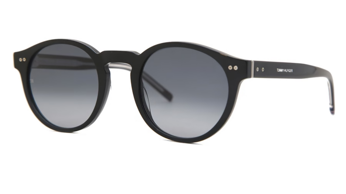 Round sunglasses with a thick black acetate frame and dark gray gradient lenses, featuring gold-tone rivets